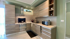 A modern kitchen with a gas stove, microwave, and built-in oven. - Il Bumbunin di Collegno – Free Parking in Central Location (Collegno)