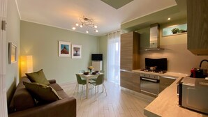 A modern apartment with a dining area, a sofa, a kitchen with a stove, and a TV. - Il Bumbunin di Collegno – Free Parking in Central Location (Collegno)