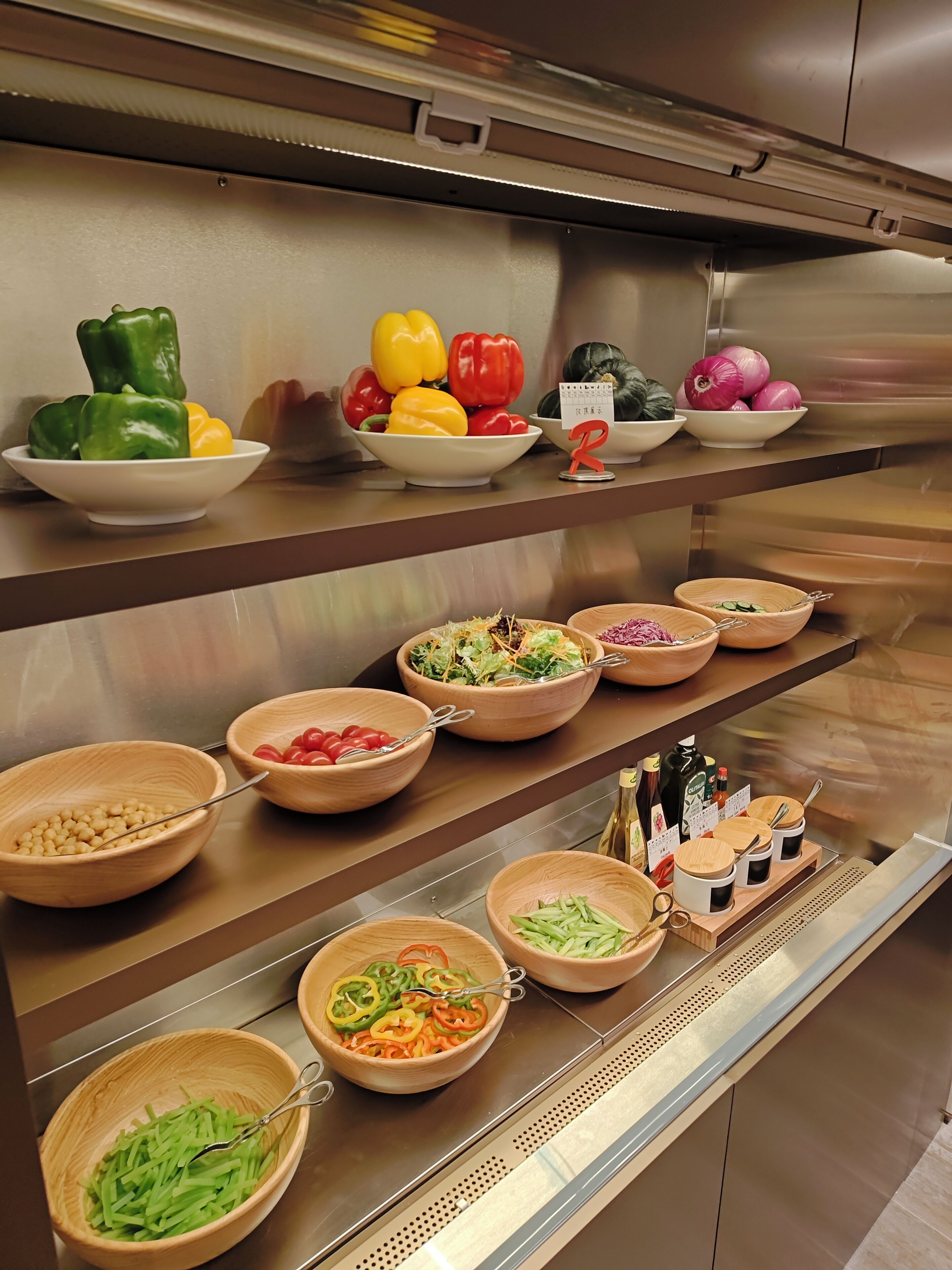 A kitchen counter with various bowls containing vegetables, a calendar, and condiments.