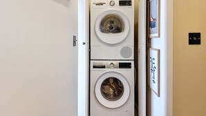 Ein Waschraum mit zwei übereinander gestapelten Bosch-Waschmaschinen, einer Tür und einem an der Wand befestigten Lichtschalter.