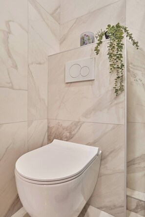 Ein Badezimmer mit Toilette, Marmorwänden und einer Pflanze.