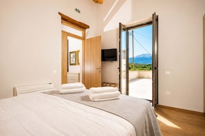 Ein Schlafzimmer mit Bett, zwei Handtüchern, einem Fernseher und einem Balkon mit Bergblick.