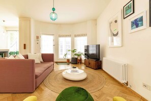 Un salon avec un canapé, une table basse, un téléviseur et un radiateur.