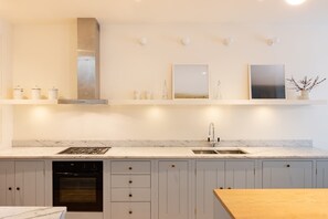 A modern kitchen with a built-in oven, a stainless steel range hood, a double sink, and a wooden countertop. - South Kensington - Mews House, Sleeps 6 (Greater London)
