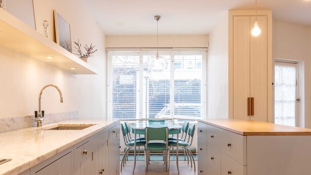 Una cucina moderna con isola centrale, lavello integrato e zona pranzo con sedie.