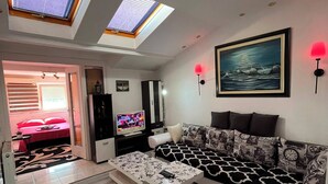 Een moderne woonkamer met een bank, een salontafel, een televisie en een schilderij aan de muur.