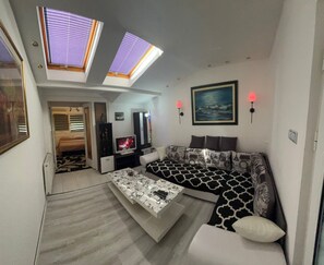 A compact living space with a sofa, a coffee table, a TV, and a painting on the wall. - 2-bedroom 1-living room apartment in beautiful area with AC near the Belgrade. (Pancevo)
