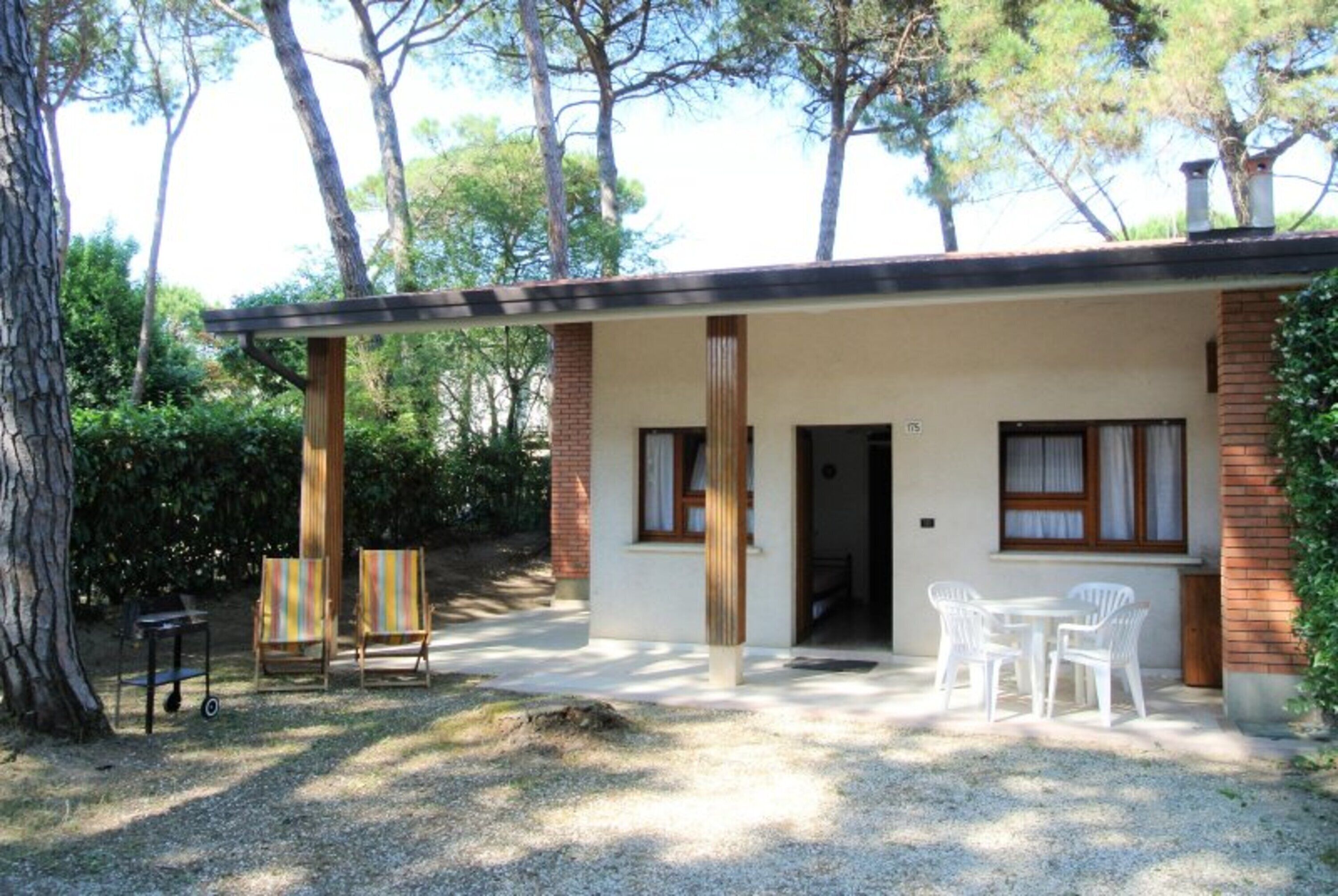 A small building with a covered patio, two chairs, and a table.