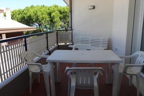 A balcony with a white table and chairs, a white bench, and a railing. - Cozy flat steps away from Lignanos golden beach (Lignano Sabbiadoro)