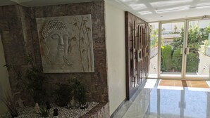 Ein modernes Interieur mit einer Steinsäule, einem großen Buddha-Gemälde und einer Glastür zum Außenbereich.