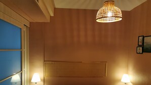 Ein Hotelzimmer mit einem Bett, zwei Nachttischlampen, einem großen Fenster und einer dekorativen Deckenleuchte.