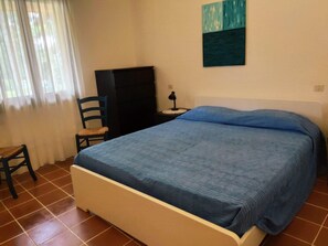 Un dormitorio con una cama, una silla, un escritorio y un cuadro en la pared.