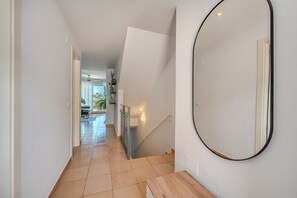 Ein Flur mit einer Treppe, einem runden Spiegel und Blick in einen Essbereich.