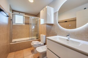 A modern bathroom with a bathtub, toilet, and sink, featuring a large mirror and a shower enclosure. - LXR Arcadia 2-Bedroom Apartment with Ocean Views (Benalmádena)