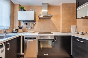 A modern kitchen with stainless steel appliances, a built-in oven, and a range hood. - LXR Arcadia 2-Bedroom Apartment with Ocean Views (Benalmádena)
