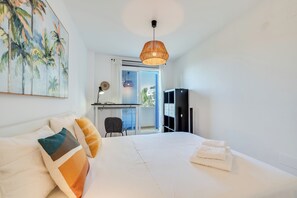 Ein Hotelzimmer mit Bett, Schreibtisch, Sessel, Fernseher und einem Balkon mit Blick.