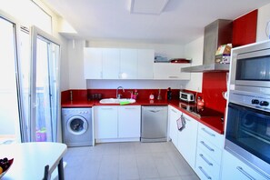 A compact kitchen with a washing machine, dishwasher, microwave, and oven.
