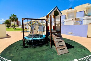Un parque infantil con una estructura para escalar y un tobogán.