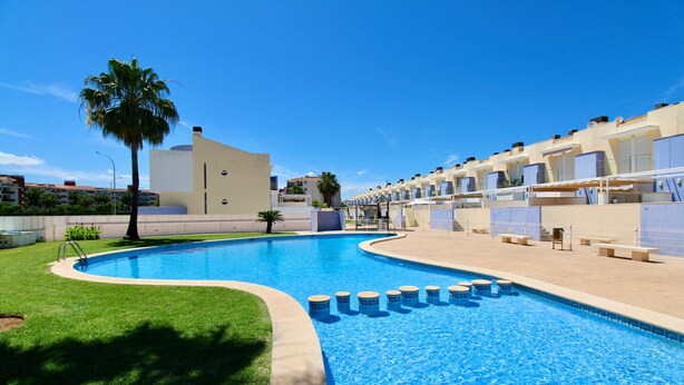 A swimming pool with a palm tree, a building with balconies, and a clear blue sky. - Holiday Home 'Grecia' with Mountain View, Wi-Fi and Air Conditioning (Vergel)