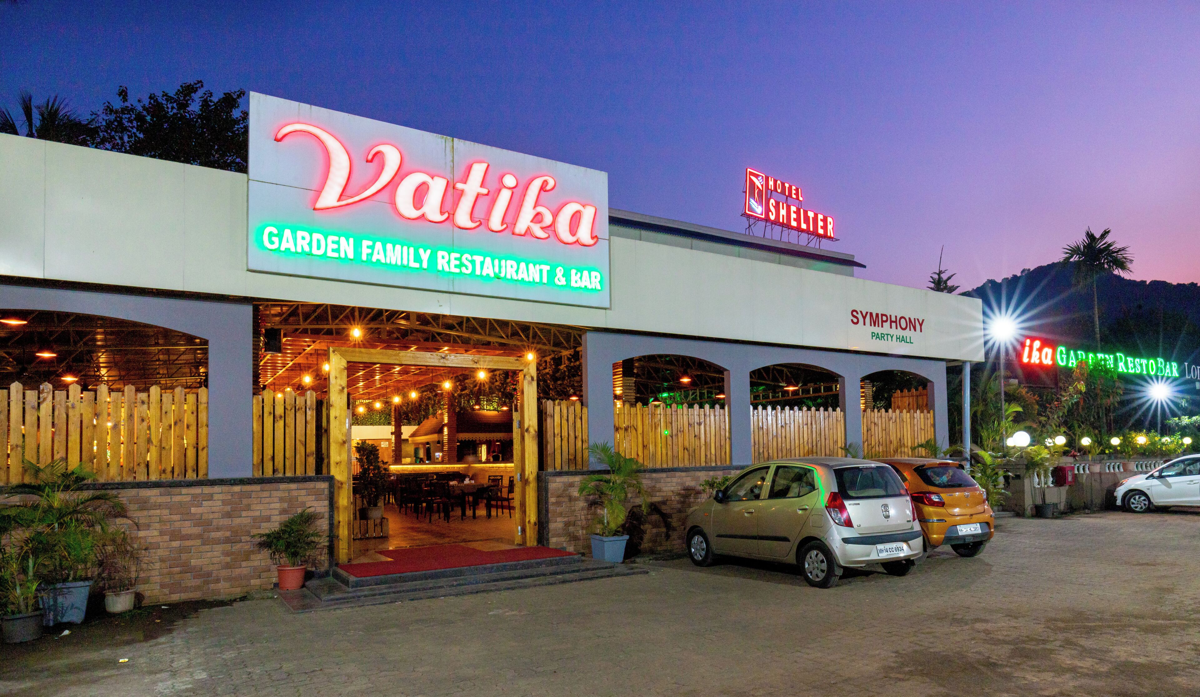 A restaurant named 'Vatika' with a visible entrance and a parking area with cars.