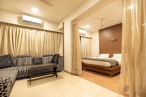 Un dormitorio con cama, sofá, mesa de centro y cortinas.