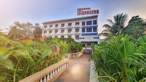 Un hotel con un letrero que dice 'HOTEL SHELTER', un edificio de varios pisos y un camino que lleva a la entrada.