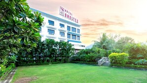 Un hotel con un letrero que dice 'HOTEL SHELTER', rodeado de abundante vegetación y un césped cuidado.