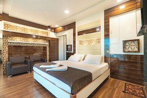 Una habitación de hotel moderna con una cama grande, un sofá, un televisor y un diseño de pared estampado.