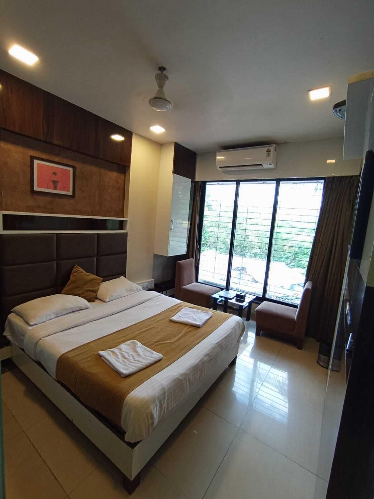 A hotel room with a large bed, a desk, a chair, and a window with a view.