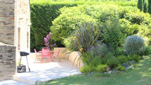 A garden patio with a stone wall, a table, and two chairs.