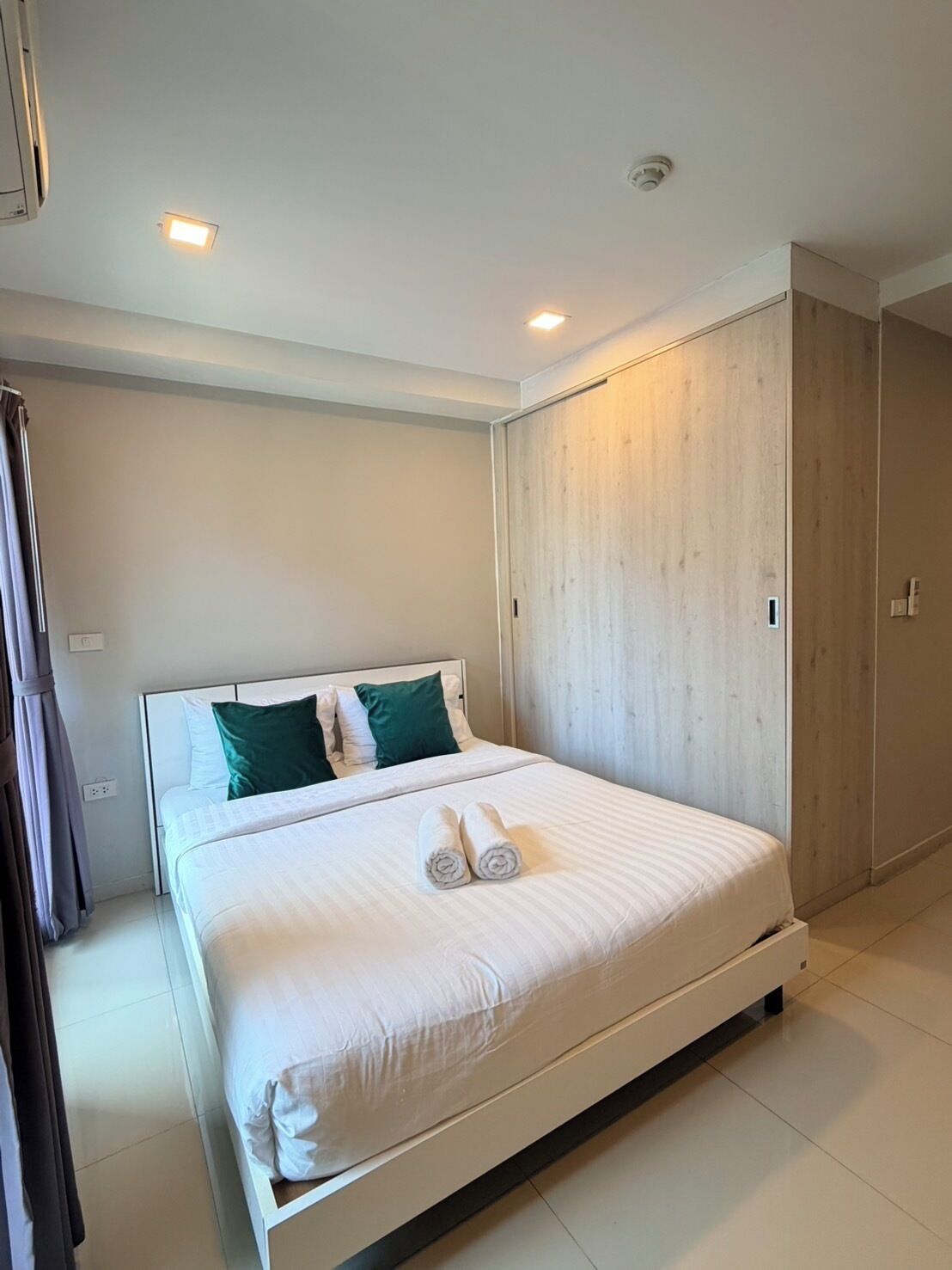 A hotel room with a bed, a wooden wardrobe, and a bathroom.