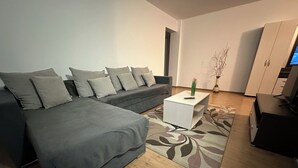 Ein modernes Wohnzimmer mit einem grauen Sofa, einem weißen Couchtisch und Holzboden.