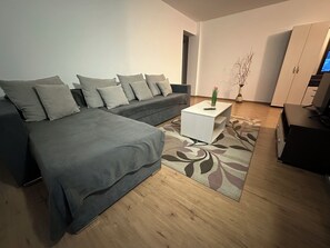 A modern living room with a grey sofa, a white coffee table, and a wooden floor. - Alexys Residence 4 cozy apartment in welcoming Iași with AC (Iași)