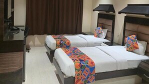 A hotel room with two beds, a desk, an air conditioning unit, and a ceiling fan. - Hotel Santoor - near Geeta bhawan square (Indore)