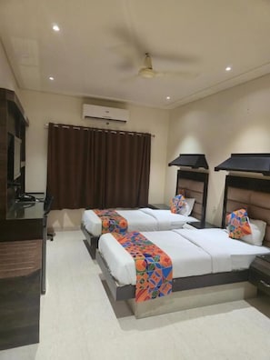 A hotel room with two beds, a desk, an air conditioning unit, and a ceiling fan. - Hotel Santoor - near Geeta bhawan square (Indore)