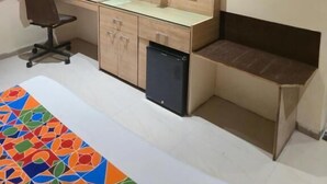 A hotel room with a bed, a desk with a computer, a television, and a small refrigerator. - Hotel Santoor - near Geeta bhawan square (Indore)