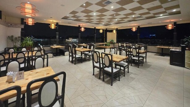 A restaurant with multiple tables and chairs, a checkered ceiling, and pendant lighting. - Hotel Santoor - near Geeta bhawan square (Indore)