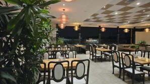 A restaurant with multiple tables and chairs, potted plants, and hanging pendant lights. - Hotel Santoor - near Geeta bhawan square (Indore)