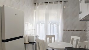 A modern kitchen with a refrigerator, a dining table with chairs, and a black countertop.