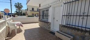 A residential area with a white house, a gated entrance, a table with chairs, and a stop sign. - Apartment in A Hotel 'Las Calas A' with Shared Pool, Wi-Fi and Air Conditioning (Torrevieja)