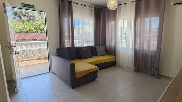A room with a sofa, curtains, a glass table, and a door labeled 'SALIDA'.