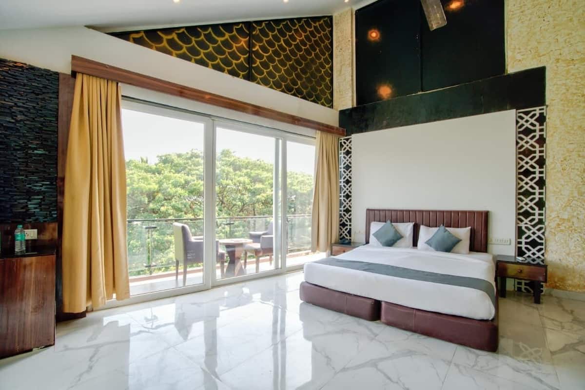 Un dormitorio con una cama grande, un balcón con vistas a la vegetación y un diseño moderno con techo estampado.