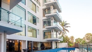 Un hotel moderno con piscina, varios balcones y fachada de vidrio.