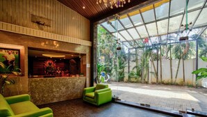 Un área de recepción con mostrador, sillas verdes y puerta de vidrio que da al exterior.