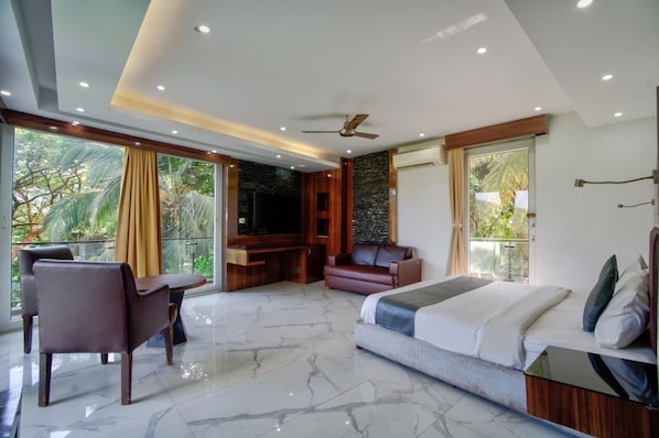 A modern bedroom with a large bed, a seating area, and a TV.