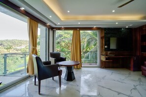 A spacious room with a large window, a round table, and two chairs. - Regal Sands Hotel  (Calangute)