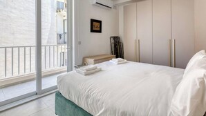 Ein Hotelzimmer mit Bett, Nachttisch, Schrank und Blick durch eine Glastür.