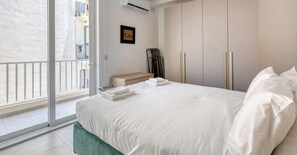Ein Hotelzimmer mit Bett, Nachttisch, Schrank und Blick durch eine Glastür.