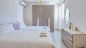 Ein Hotelzimmer mit zwei Betten, einem Schrank, einem Schminktisch und einem Spiegel.