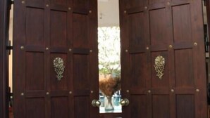Un conjunto de puertas dobles de madera con un ventanal central, que dan a un espacio exterior.